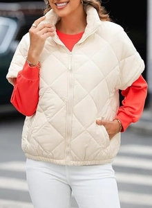 Detailed view of the diamond quilted pattern and stand collar on this cream puffer vest