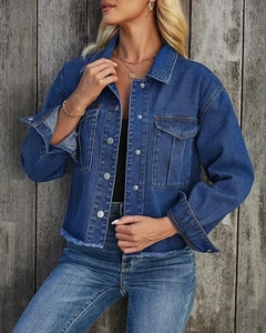 Detailed view of dark blue denim jacket featuring raw hem edges and metallic buttons