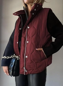 Detail view of wine red quilted vest with wave stitching, zipper and snap button closure