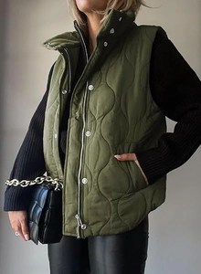 Detail view of wave-quilted olive green puffer vest with stand collar and metallic buttons