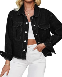 Detail of black cropped denim jacket showing raw hem and chest pockets with metal buttons