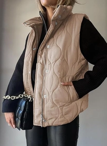 Detail of wavy quilted beige vest with high collar and snap-button zipper closure
