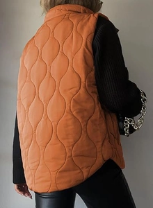Rear view of bright orange quilted puffer vest with wave patterns and stand collar