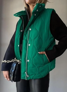 Detail of green quilted puffer vest featuring wave pattern and dual zipper snap closure