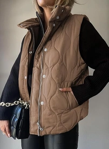 Detailed view of women's brown quilted vest featuring stylish wave pattern and zipper closure