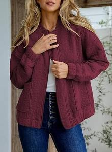 Close-up of wine red quilted jacket featuring floral texture and smooth metal zipper detail
