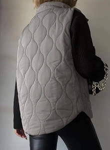 Rear view of grey quilted vest with wave pattern stitching and high neck collar