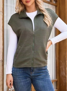 Detail view of olive green quilted vest featuring stand collar and functional zip pockets