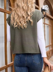 Rear view of women's dark green quilted waffle knit vest with side pockets in street style