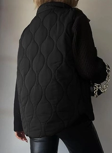 Detail view of wave-pattern quilting and stand collar on the black winter vest