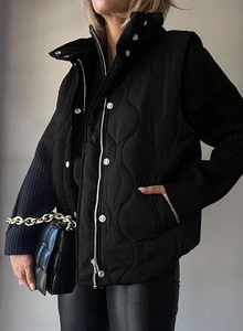 Detail view of wavy quilted black vest with zipper, snap buttons and side pockets