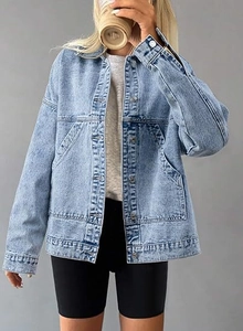 Detail of light blue oversized denim jacket featuring metal buttons and large front pockets