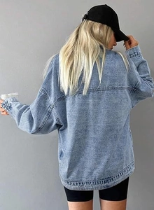 Detailed back view of a light blue washed denim jacket showing shoulder stitching and cuffs