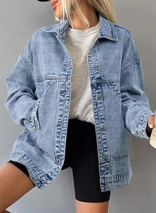 Detail of light blue oversized denim jacket featuring metal buttons and washed texture