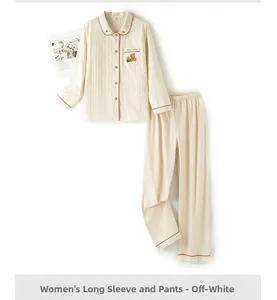 Flat lay detail of women's long sleeve cream pajama set with red piping and bear embroidery