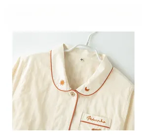 Detail of cotton loungewear featuring striped texture and bear embroidery with orange piping