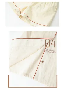 Close-up of cream cotton pajama hem with orange piping and natural wooden buttons