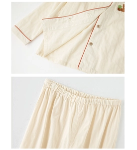Detail of cotton pajama set with bear embroidery, wooden buttons, and red piping trim