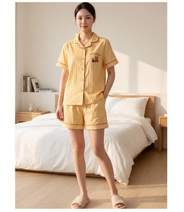 Close-up of yellow striped cotton pajamas featuring cute bear and plant embroidery detail