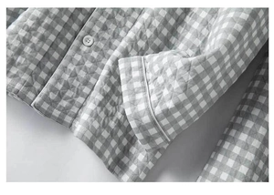 Macro detail of quilted grey gingham pajamas with white piping and round button closure