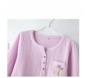 Détail du haut de pyjama en coton violet avec col Henley, boutons bois et broderie fleur