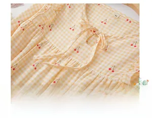 Détail du col de pyjama avec motif à carreaux jaunes, imprimé cerise et dentelle