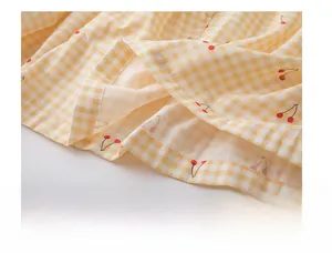 Détail des coutures précises sur l'ourlet du pyjama en coton à carreaux jaune et cerises