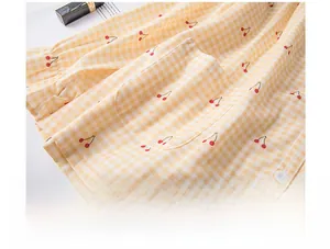 Detail of cherry print cotton pajama with ruffled pocket on yellow gingham fabric