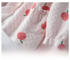 Detail of pink quilted cotton jacket with apple print, ruffled cuffs and scalloped pockets