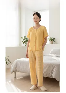 Détail d'un pyjama en coton jaune clair avec col en dentelle et pantalon à carreaux