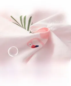 Gros plan sur un tissu en gaze de coton double couche avec flamant rose et feuilles vertes