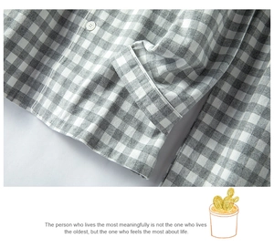 Detail eines grau-weiß karierten Baumwollpyjamas mit weißem Knopf und Flanellstruktur