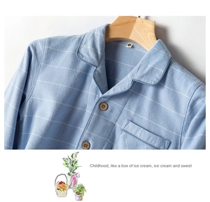 Detail of light blue plaid cotton pajama top featuring brown buttons and chest pocket