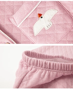 Detail of bird embroidery on pocket and elastic waistband of pink herringbone pajamas