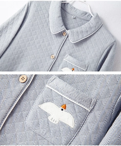 Detail of embroidered bird pattern and wooden buttons on blue herringbone pajama set