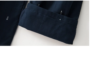 Close-up of small fish embroidery on navy blue cotton pajamas with neat hemline stitching
