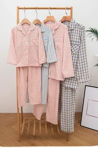 Detail of multi-color plaid cotton pajama sets hanging on wooden hangers for couples