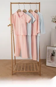 Detail view of light pink and blue cotton pajamas sets on wooden hangers in home setting