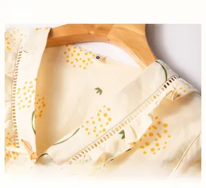 Detail of yellow cotton pajama collar with hollow lace trim and small ribbon bowknot