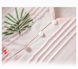 Détail de l'encolure à volants et boutons blancs sur chemise de nuit en coton rose