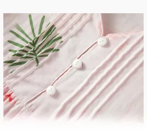 Detail of pink cotton pajama top featuring white buttons and green palm leaf patterns