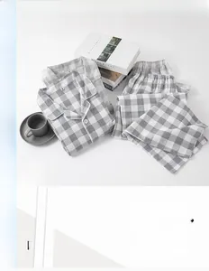 Flat lay of grey plaid cotton pajama set with lounge props on a white background