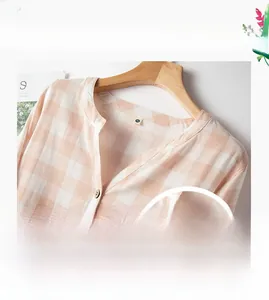 Dettaglio dello scollo a V e del bottone in legno su una camicia da notte in cotone rosa