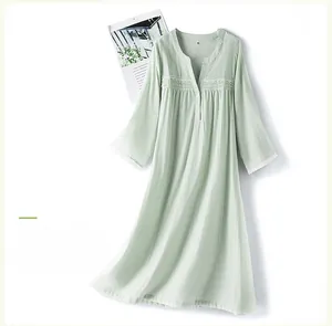Detail of V-neck button closure and white lace trim on a light green cotton nightdress