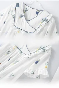 Close-up of V-neck and ruffled sleeves on white cotton dress with floral potted plant prints