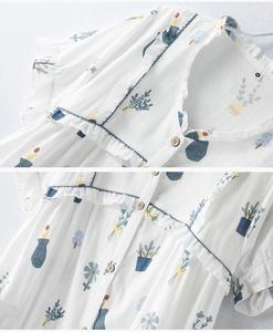 Close-up of cotton fabric texture with green plant print and wood buttons on white top