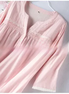 Detail of pink cotton gauze nightgown featuring V-neck, lace trim, and white buttons