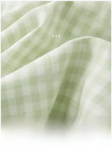 Close-up of light green plaid 100% cotton fabric showing soft breathable texture
