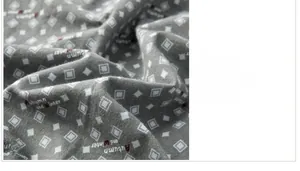 Detail of grey three-layer padded cotton fabric with geometric pattern and text print