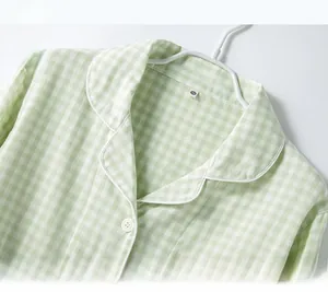 Detail of green gingham pajama collar with white piping and resin buttons